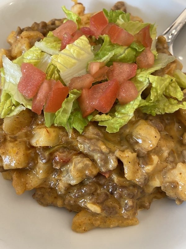 Taco Potato Casserole in a bowl with fork and lettuce and tomatoes