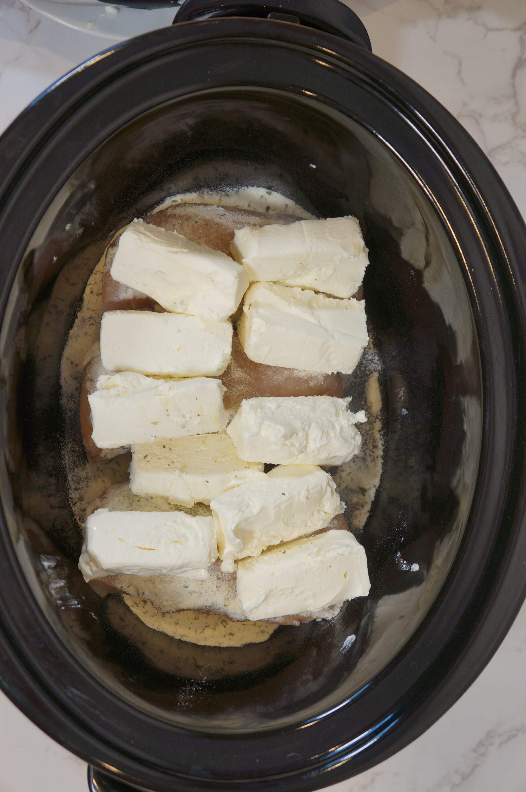 topping the crockpot chicken with cream cheese