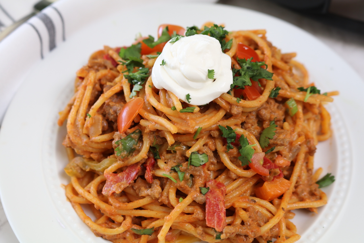 Mexican Spaghetti on a white plate topped with sour cream