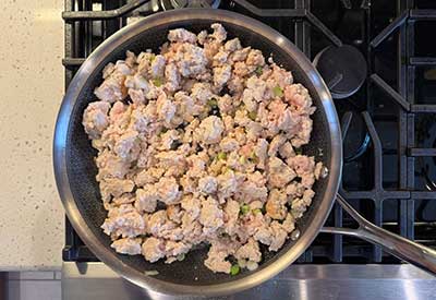 Cook the chicken on the stove in a large skillet on medium-high heat. Add the white parts of the green onions, garlic, and ginger. Cook for 30 more seconds.